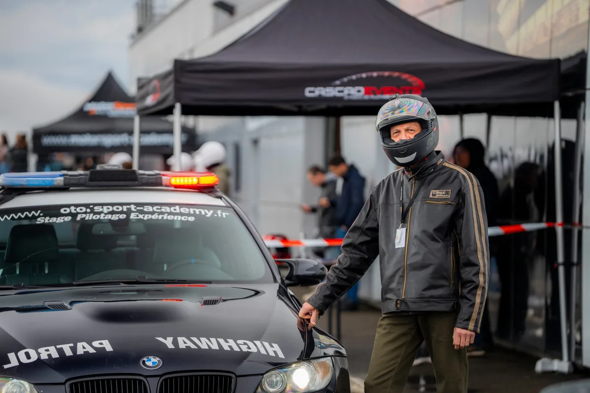 Casque sur la tête, à côté de la BMW M3, au paddock