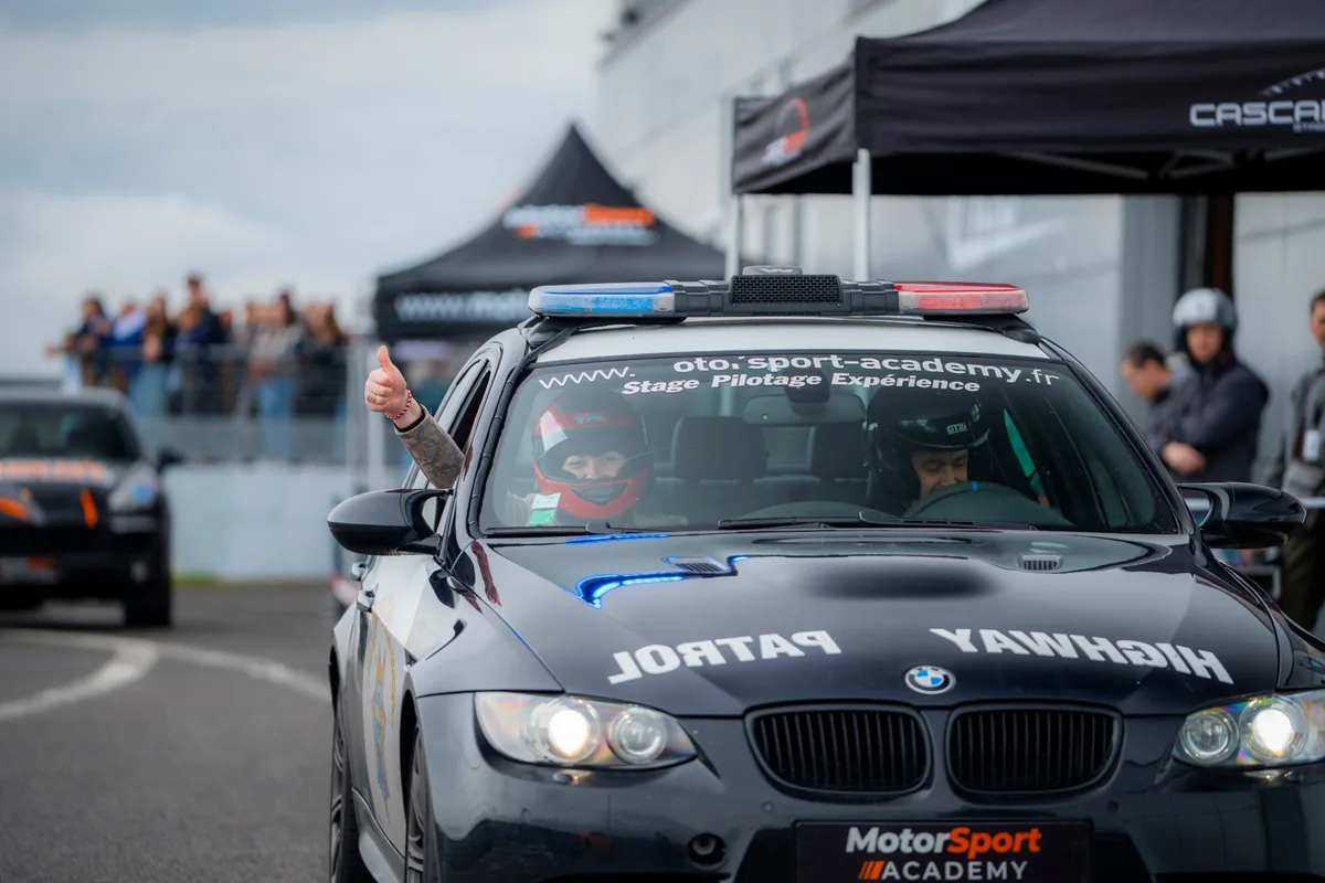 Pouce levé depuis la place passager de la BMW M3, casque sur la tête