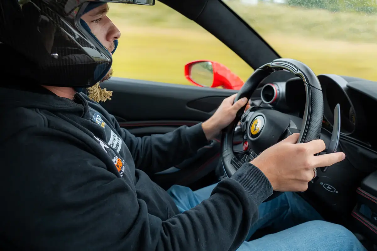 Un pilote casqué au volant, les mains à dix heures dix