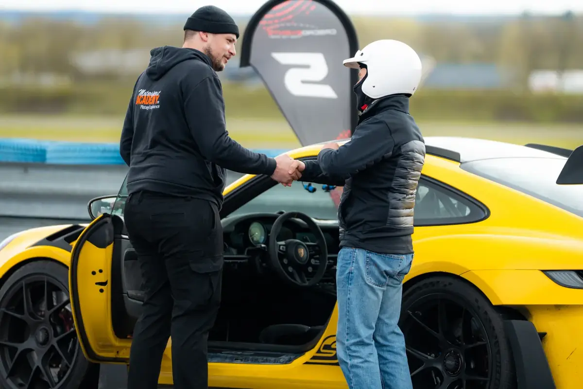 Le moniteur accueille le pilote devant la voiture
