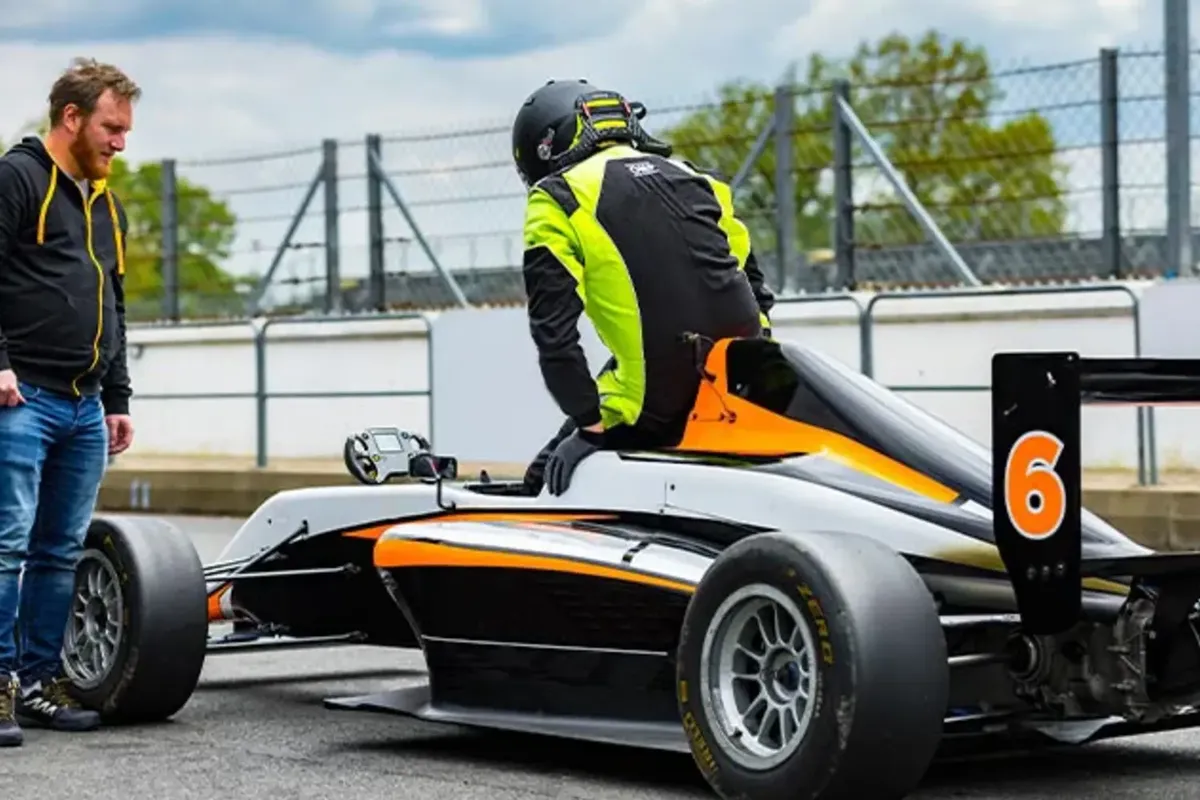 Un pilote s’installe dans la Formule 4, un moniteur à côté de lui